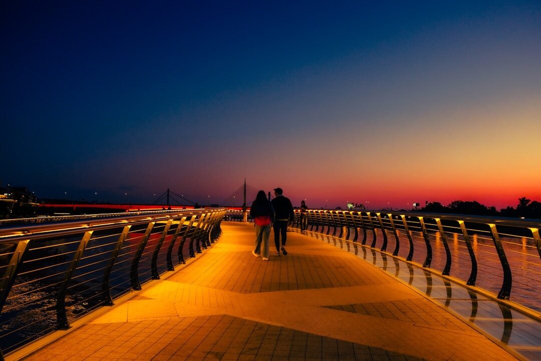 Couple walks on bridge during a beautiful sunset.