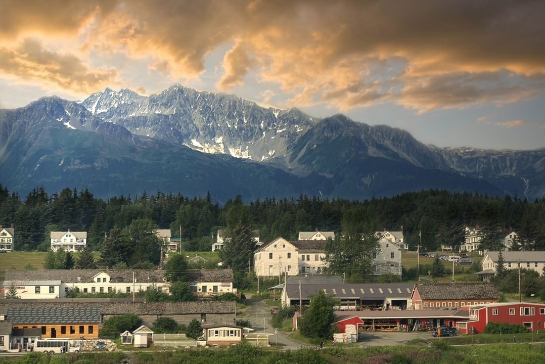 Idyllic small town nestled beneath dramatic Alaskan mountain range at sunset.