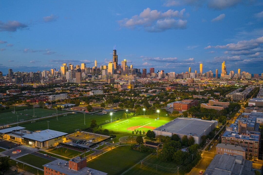 City skyline at dusk with illuminated baseball fields.