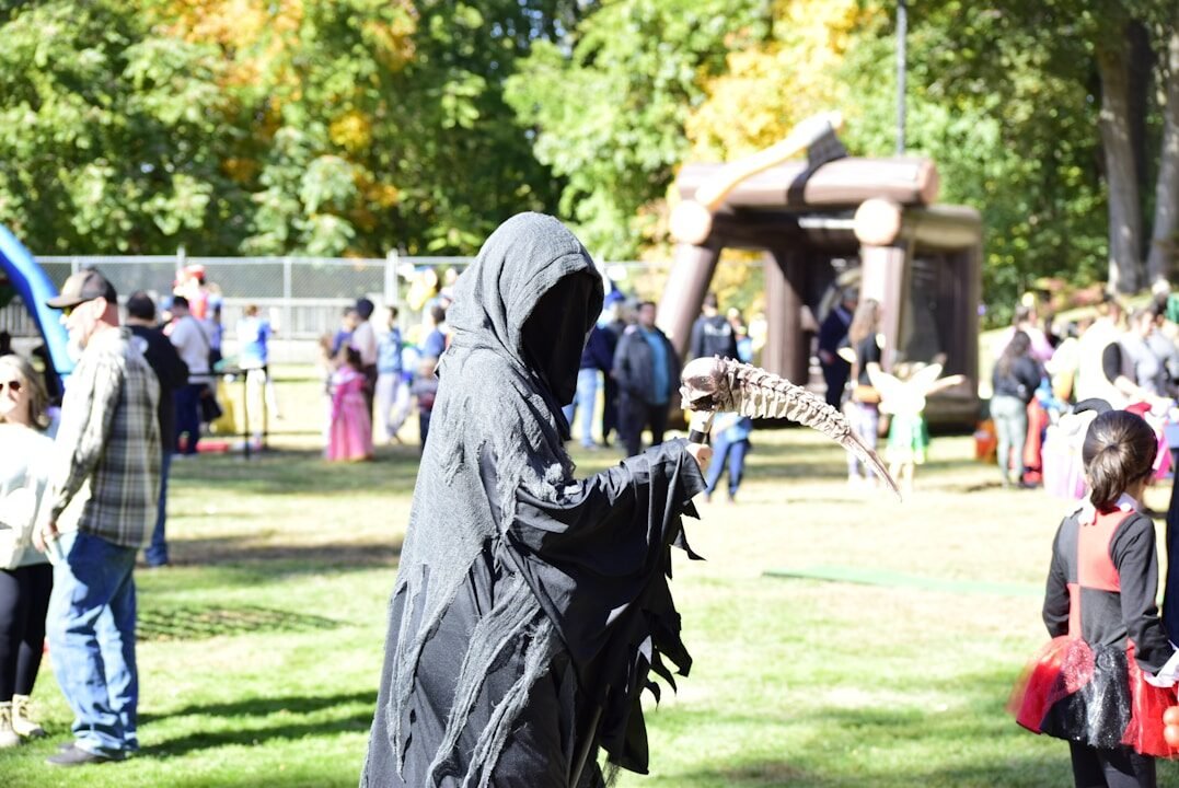 Grim reaper costume at an outdoor autumn event.