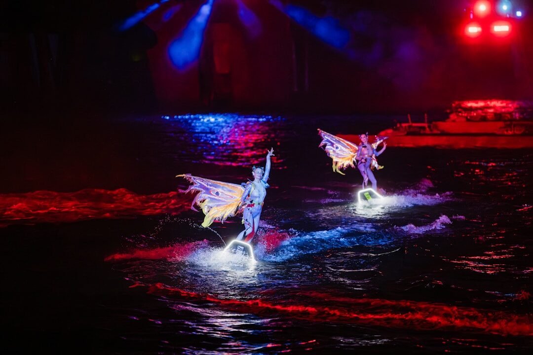 Performers with wings on water at night