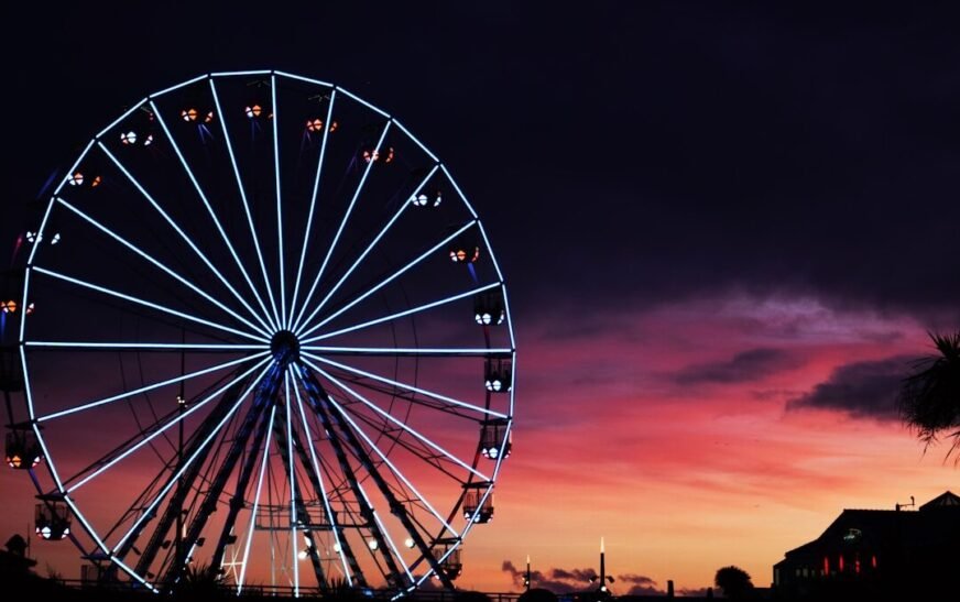 silhouette photography of lit-up ferris wheel during golden hour