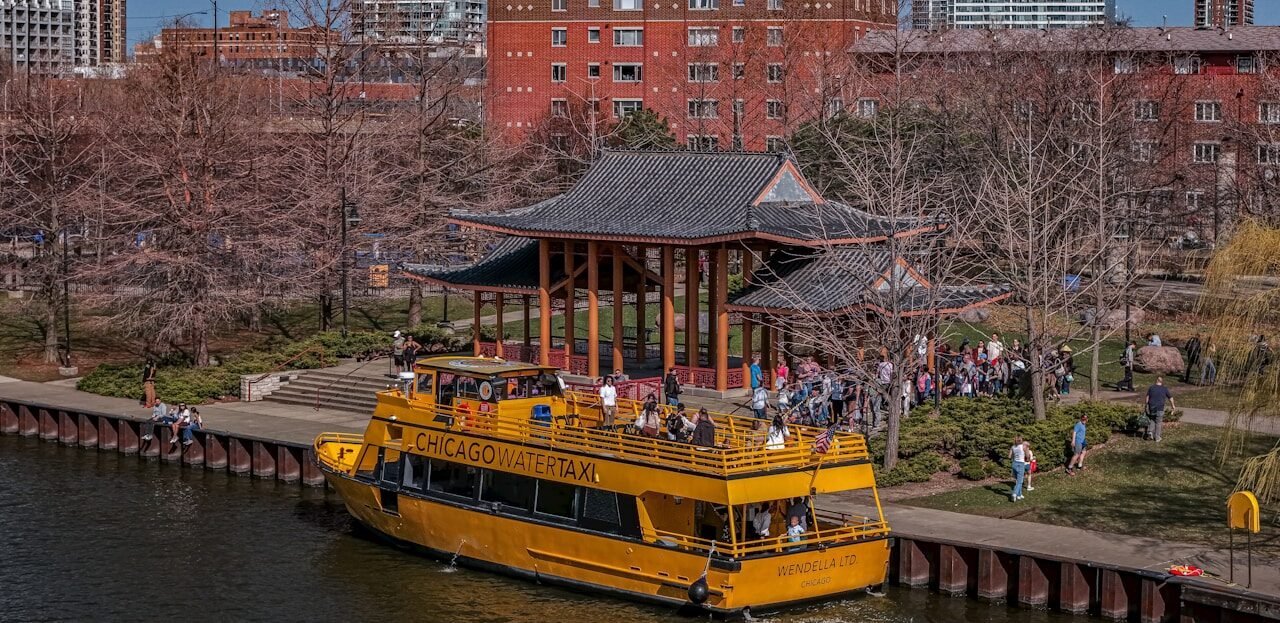 Yellow boat docked near a pagoda with people on shore.