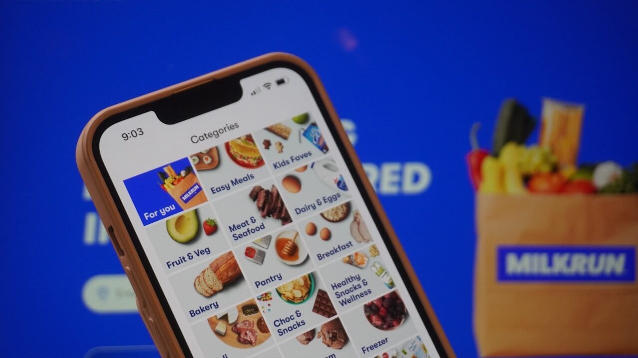 A person holding a cell phone in front of a screen