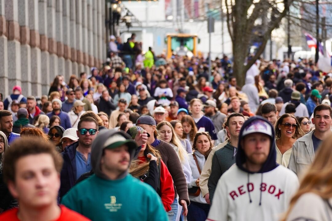 A large crowd of people walking down a city street.