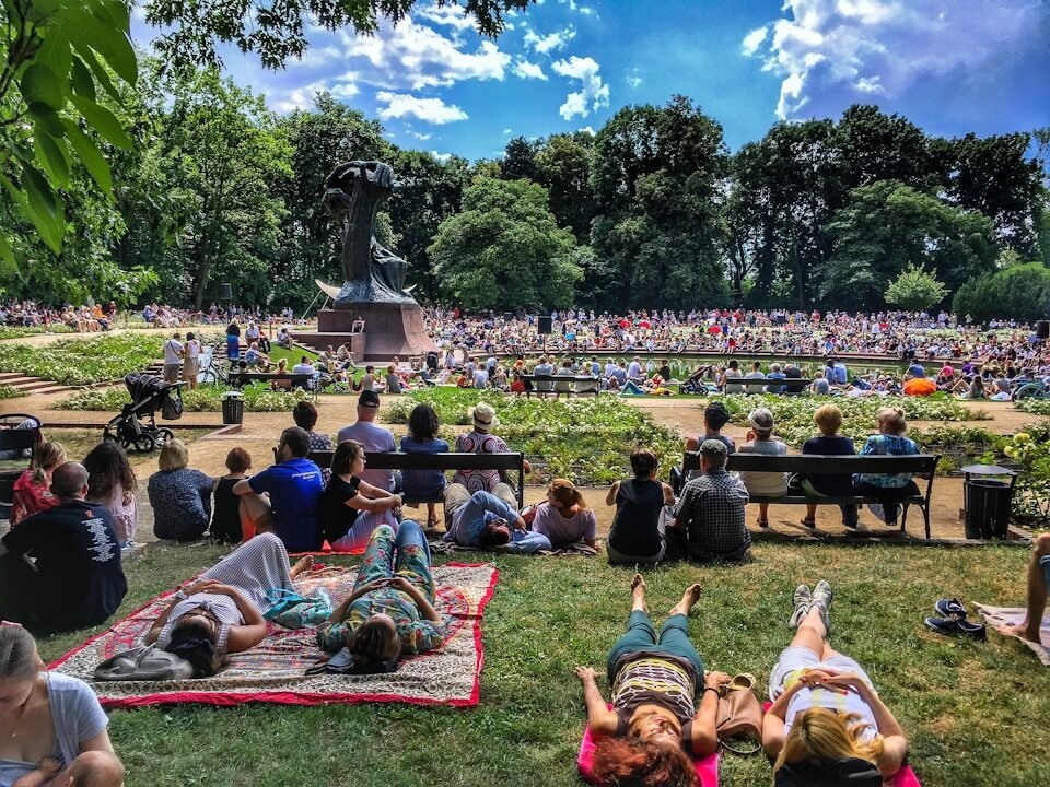 a crowd of people sitting on top of a lush green field