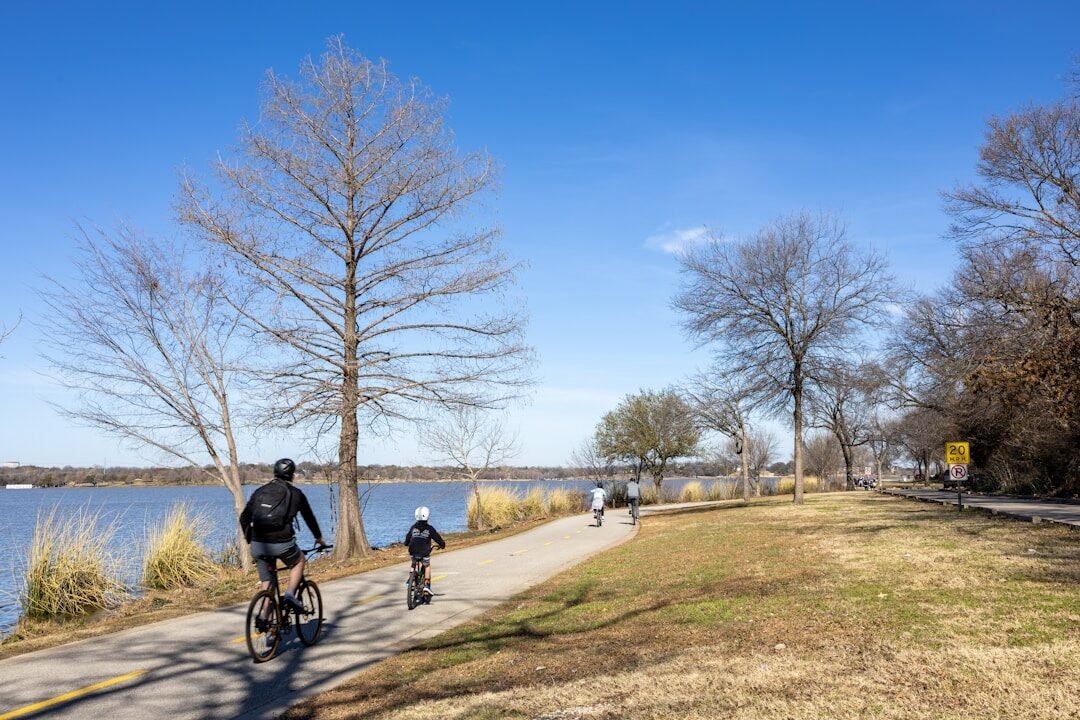 A man riding a bike down a road next to a lake