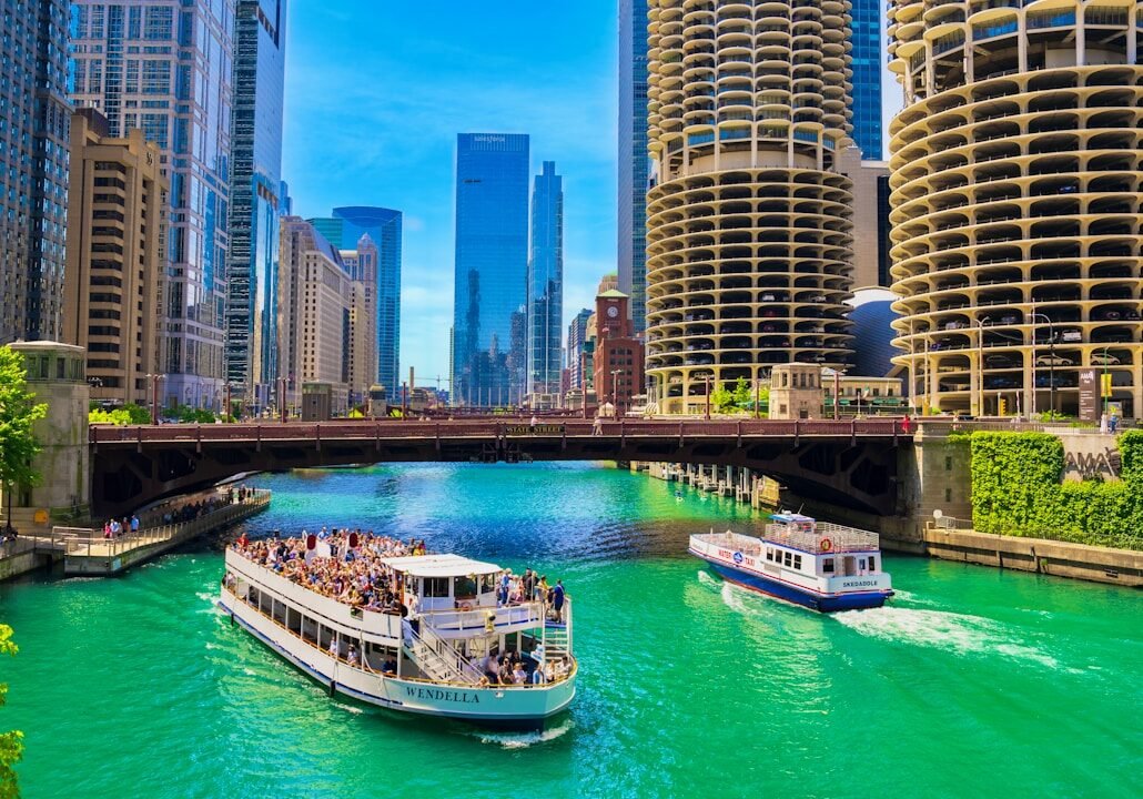 A river filled with lots of green water next to tall buildings