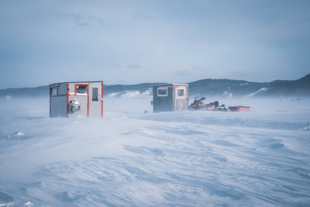 a couple of small buildings sitting in the middle of a snow covered field